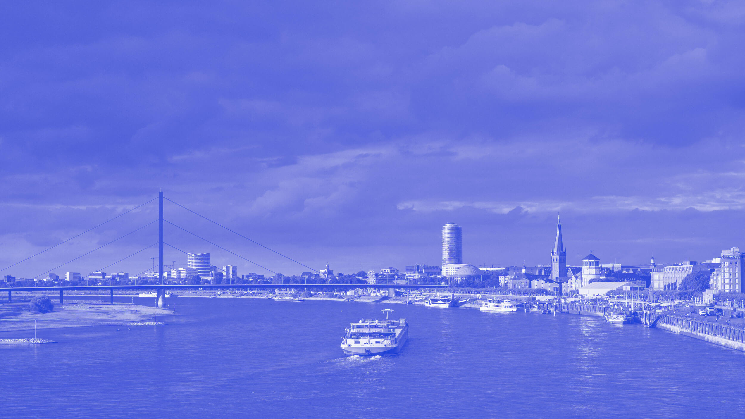 Panorama von Düsseldorf mit der Rheinkniebrücke, der Skyline und einem Schiff auf dem Rhein.