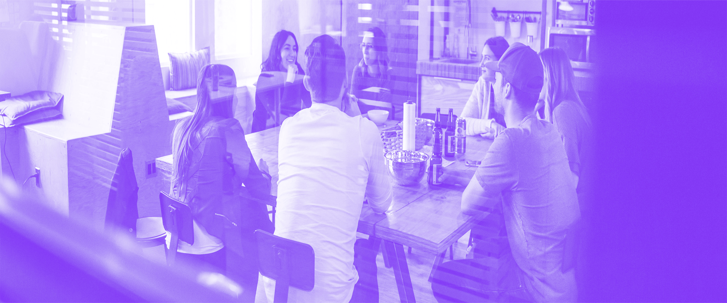 Team diskutiert in einer modernen Büroumgebung an einem großen Tisch – symbolisiert Zusammenarbeit und Teamwork.