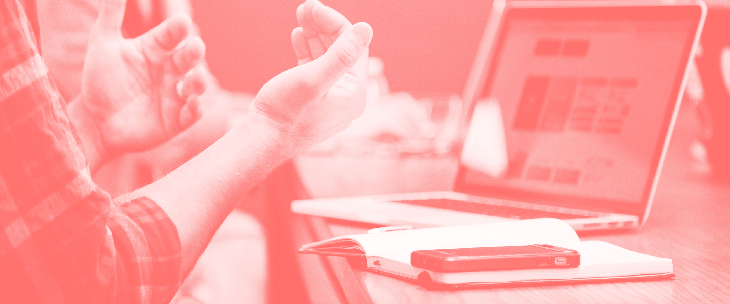 Nahaufnahme einer Hand in einer Diskussion mit Laptop und Notizbuch im Hintergrund – symbolisiert Kommunikation und Ideenaustausch.