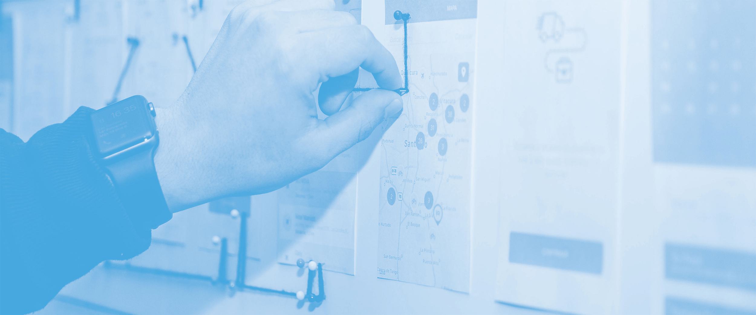 Hand befestigt ein Element an einer Pinnwand mit Karten und Verbindungen – symbolisiert Planung und strategische Organisation.