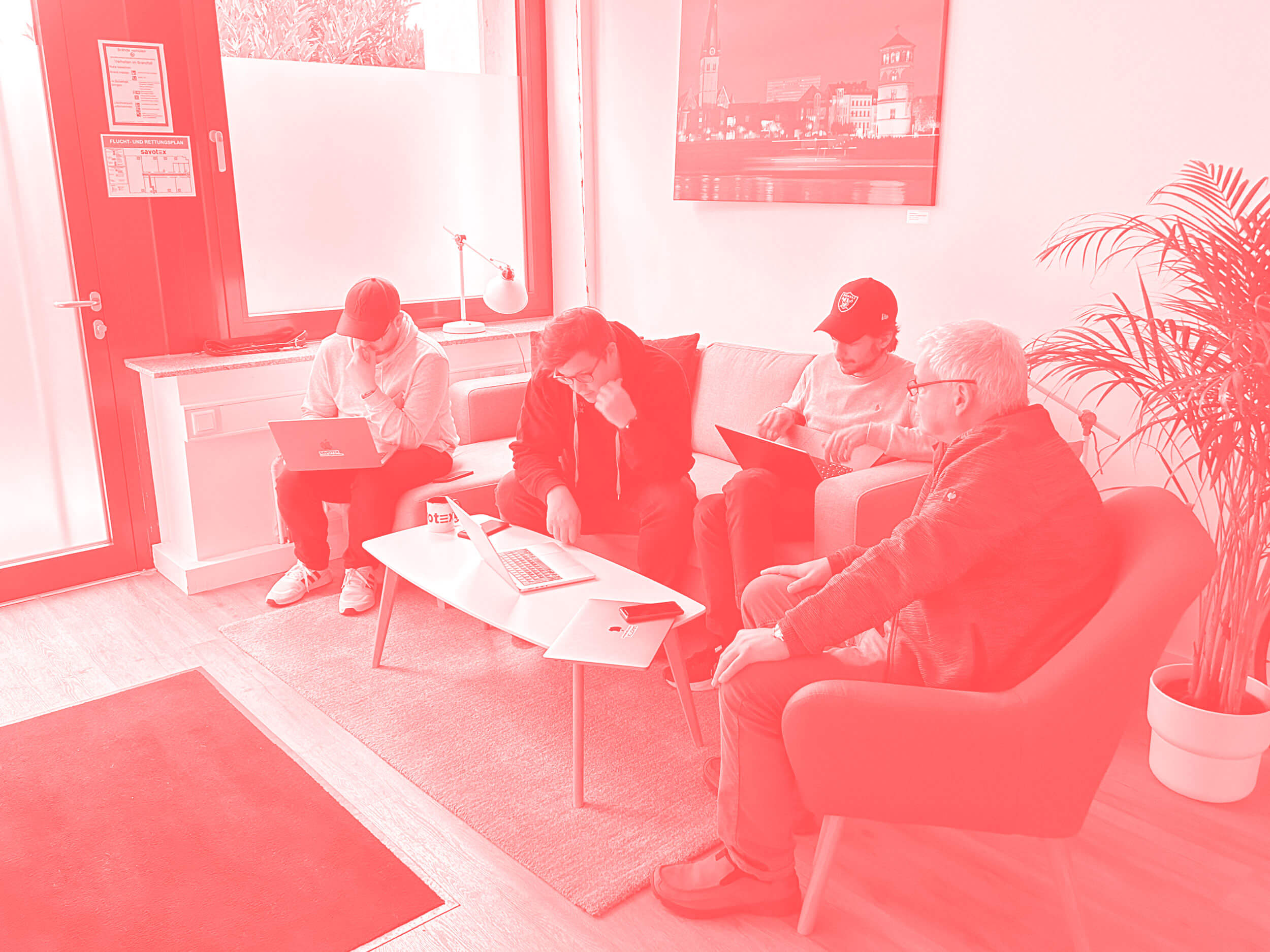 Savotex-Mitarbeiter bei einer Teamdiskussion mit Laptops in einem modernen Büro – symbolisiert Zusammenarbeit und innovative Lösungsentwicklung.