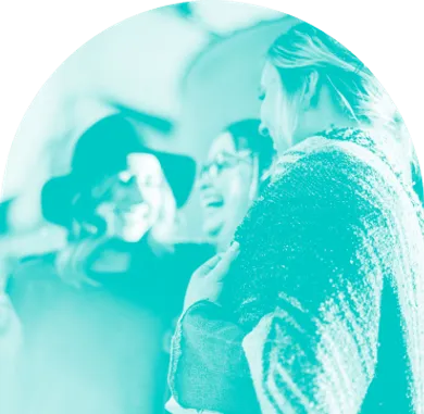 Drei Frauen lachen und genießen ein Gespräch in entspannter Atmosphäre – symbolisiert Gemeinschaft und positive Interaktion.