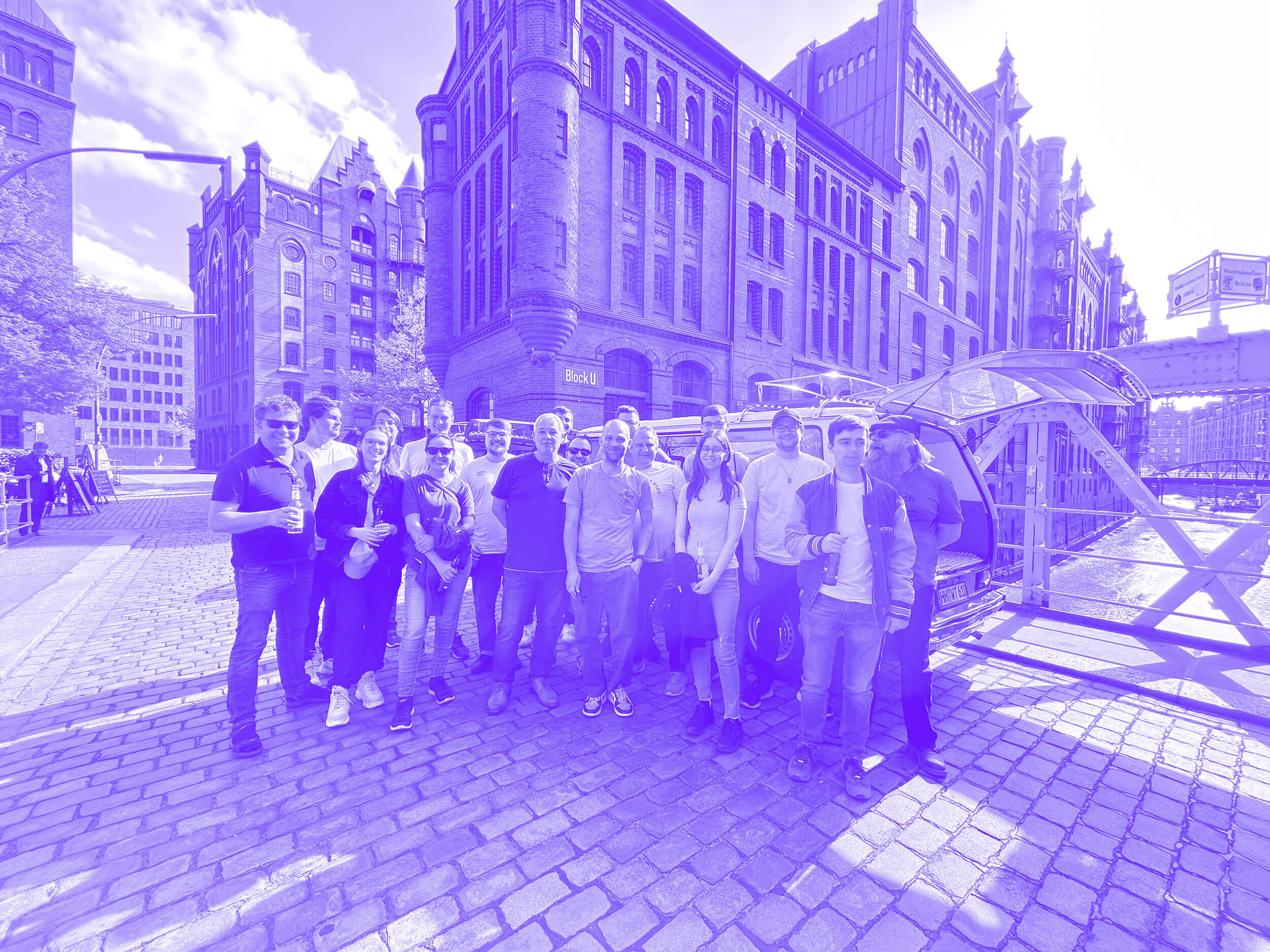 Das savotex Team vor einer historischen Backsteinarchitektur in einem sonnigen Stadthintergrund in Hamburg bei einem unserer Firmenausflüge.