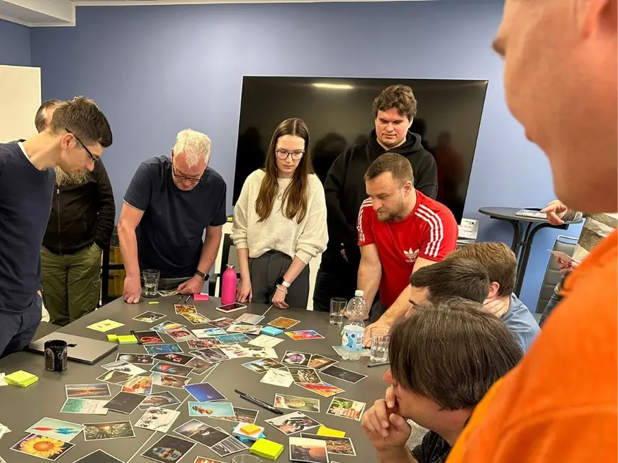 Mitarbeitende betrachten gemeinsam eine Vielzahl von Karten, um Ideen zu entwickeln – symbolisiert Kreativität und Teamwork.